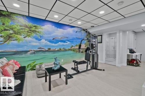 Drop ceiling with recessed lighting, wood-finish flooring, full-wall mural, and a private shower stall with a glass door - 6818 Evans Wynd Nw, Edmonton, AB 