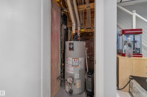 Utility closet featuring a water heater, visible plumbing infrastructure, and exposed framing - 6818 Evans Wynd Nw, Edmonton, AB 