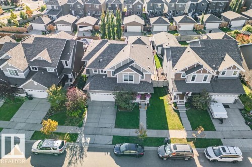 Aerial perspective featuring detached single-family residences with attached multi-car garages, asphalt shingle roofs, private concrete driveways, and manicured lawns - 6818 Evans Wynd Nw, Edmonton, AB 
