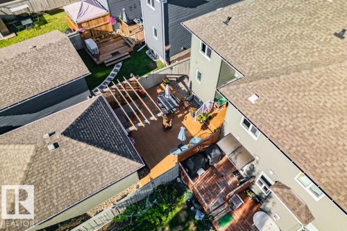 Rear yard featuring a multi-level wood deck, a wooden pergola, and perimeter wood fencing - 6818 Evans Wynd Nw, Edmonton, AB 