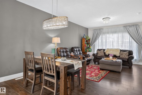 Open-concept area featuring wood-finish flooring, a custom crystal-detail oval chandelier, a secondary flush-mount crystal fixture, and floor-to-ceiling drapery hardware - 798 Berg Loop, Leduc, AB 