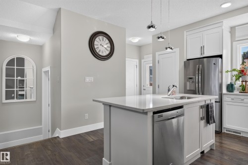 Kitchen island featuring stone countertops, an undermount sink, and integrated stainless steel dishwasher - 798 Berg Loop, Leduc, AB 