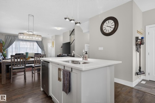 Kitchen island featuring a dual-basin stainless steel sink, solid-surface countertop, and lower cabinetry with metallic hardware - 798 Berg Loop, Leduc, AB 