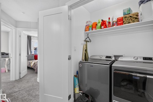Laundry alcove featuring stainless steel laundry appliances and a built-in overhead storage shelf - 798 Berg Loop, Leduc, AB 