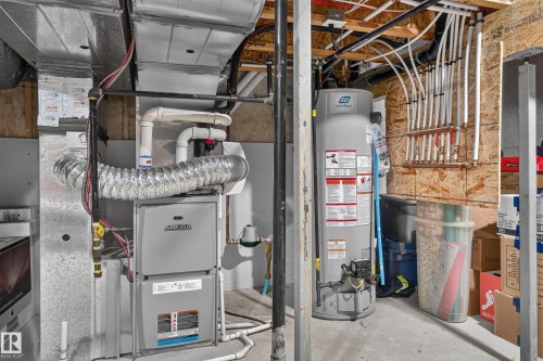 Mechanical area featuring a high-efficiency forced-air furnace, a cylindrical water heater, and a multi-port plumbing manifold system - 798 Berg Loop, Leduc, AB 