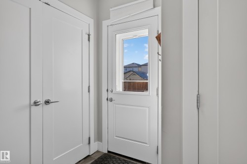 Single-panel exterior door with integrated window and polished chrome hardware, paired with two full-height interior closet doors featuring matching chrome lever handles - 798 Berg Loop, Leduc, AB 