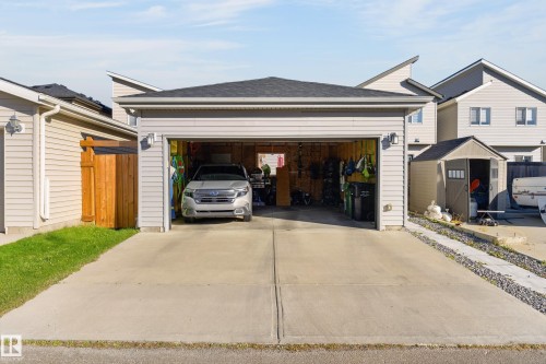 Detached garage featuring vinyl siding, asphalt shingle roofing, and a concrete driveway - 798 Berg Loop, Leduc, AB 