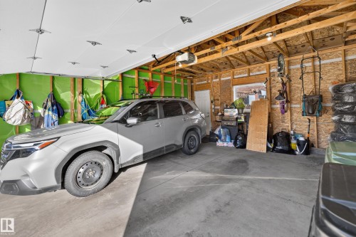 Garage space featuring exposed wood-stud wall construction, concrete flooring, overhead automatic door opener, and a singular window - 798 Berg Loop, Leduc, AB 