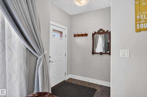 Entryway featuring wood-finish flooring, a white paneled door with a glass insert, and a wall-mounted hook rail - 798 Berg Loop, Leduc, AB 