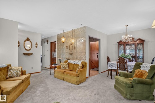 Carpeted living area with light-toned walls, featuring a separate dining space with a chandelier - 14 Sonora Drive, St. Albert, AB 