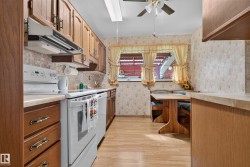 Wood-finish flooring, wood cabinetry, built-in dining nook with wood bench seating, white appliances, and a tiled backsplash - 