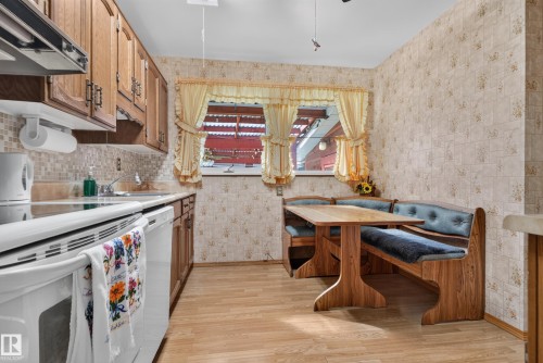 Wood-finish flooring, built-in kitchen banquette, upper and lower cabinetry, tiled backsplash, and built-in sink - 14 Sonora Drive, St. Albert, AB 