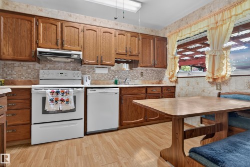 Full kitchen featuring wood-finish cabinetry, tile backsplash, built-in range, and dishwasher - 14 Sonora Drive, St. Albert, AB 