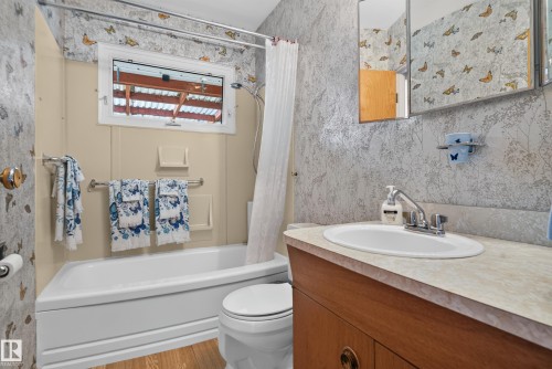 White bathtub with a shower fixture, wood-finish flooring, and a window above the bath - 14 Sonora Drive, St. Albert, AB 