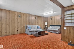 Wood-paneled walls and ceiling beams, dropped ceiling with integrated lighting, and built-in shelving - 
