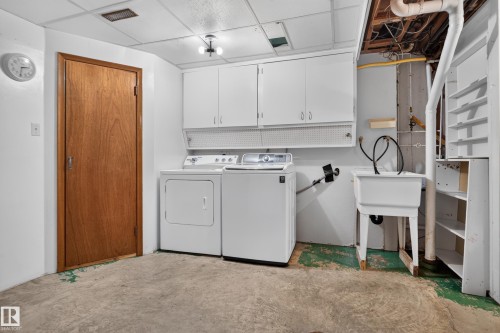 Laundry area featuring a utility sink, white upper cabinetry, and a drop ceiling - 14 Sonora Drive, St. Albert, AB 