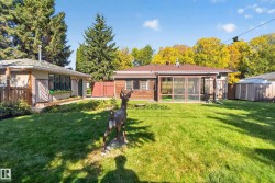 Expansive rear yard featuring a screened-in porch, mature trees, and a storage shed - 