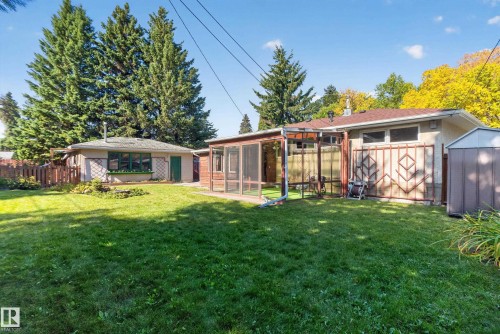 Expansive backyard featuring a green lawn, mature trees, a screened-in patio, and an additional detached structure - 14 Sonora Drive, St. Albert, AB 