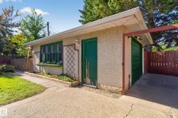 Detached accessory structure with a garage door and exterior entry, featuring a window box and concrete hardscaping - 
