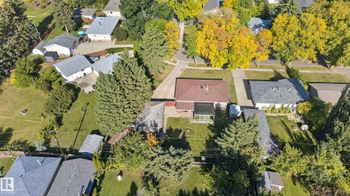 Expansive residential property featuring a primary residence with a red shingle roof, a detached garage with a gray shingle roof, and a verdant lot with mature trees - 14 Sonora Drive, St. Albert, AB 