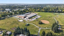 Expansive green spaces featuring a baseball diamond, paved pathways, and mature trees - 