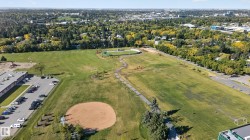 Expansive green space featuring a baseball diamond, paved walking paths, and a track - 