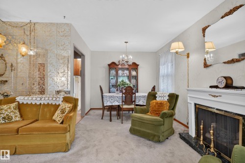 Carpeted living area featuring a fireplace with a white mantel and dark stone surround - 14 Sonora Drive, St. Albert, AB 