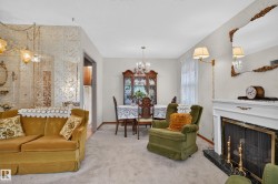 Carpeted living area featuring a fireplace with a white mantel and dark stone surround - 