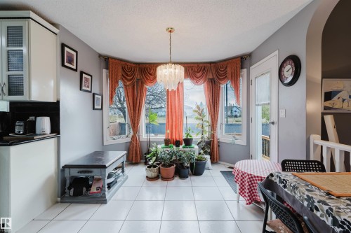 Breakfast area featuring tile flooring, a bay window with natural light, and a crystal-style chandelier - 225 Heagle Crescent Nw, Edmonton, AB 