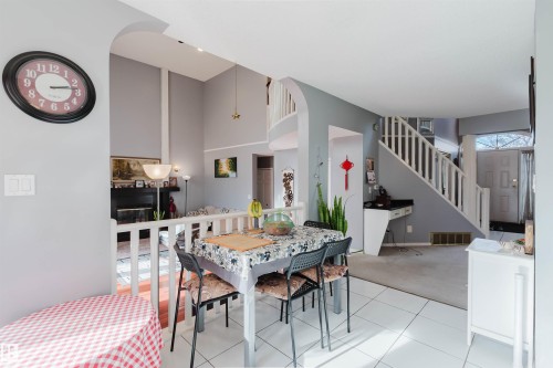 Vaulted ceilings, fireplace with black surround, white spindle staircase, arched wall opening, and tile flooring - 225 Heagle Crescent Nw, Edmonton, AB 