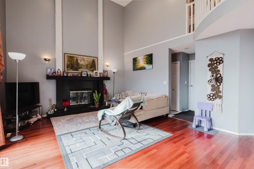 Living area featuring vaulted ceilings, wood-finish flooring, and a fireplace with a black surround and floor-to-ceiling accent columns - 225 Heagle Crescent Nw, Edmonton, AB 