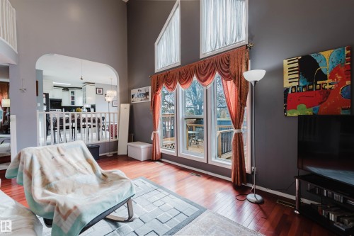 Living space featuring vaulted ceilings, floor-to-ceiling windows, wood-finish flooring, and an arched wall opening - 225 Heagle Crescent Nw, Edmonton, AB 