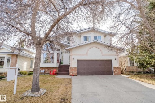 Two-story residence featuring a multi-tonal stucco and brick facade, an attached double-car garage, large picture windows, and a concrete driveway - 225 Heagle Crescent Nw, Edmonton, AB 