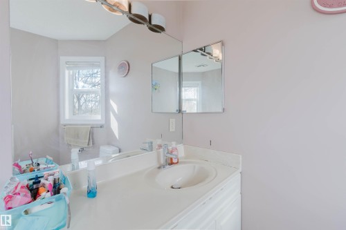 Wall-mounted mirror, integrated vanity with a molded sink, chrome faucet, and white cabinetry - 225 Heagle Crescent Nw, Edmonton, AB 