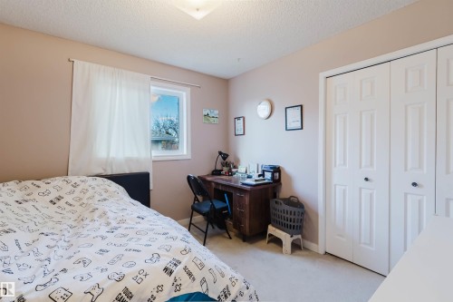 Bedroom featuring wall-to-wall carpeting, dual-pane window with white trim, and a double-door reach-in closet with six-panel doors - 225 Heagle Crescent Nw, Edmonton, AB 