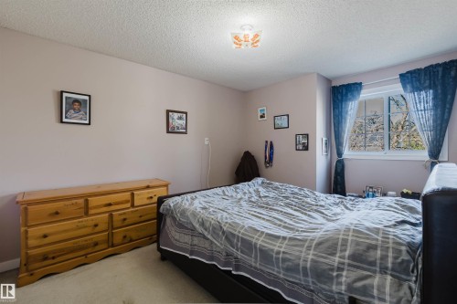 Neutral-toned room featuring a multi-pane sliding window, textured ceiling, and flush-mount decorative ceiling light fixture - 225 Heagle Crescent Nw, Edmonton, AB 