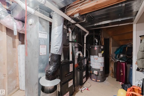 Mechanical utility area featuring a central furnace unit, water heater, metal ductwork, and exposed wood framing - 225 Heagle Crescent Nw, Edmonton, AB 