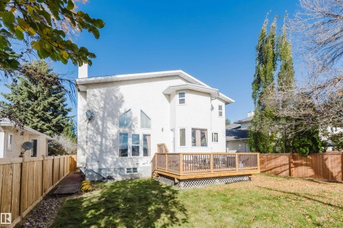 Stucco exterior featuring multi-pane geometric windows, a raised wood deck with latticework skirting, and perimeter wood fencing - 225 Heagle Crescent Nw, Edmonton, AB 