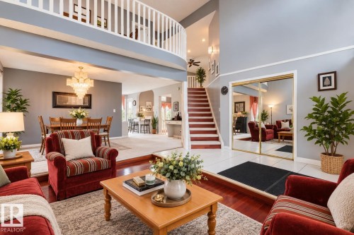 Two-story foyer featuring white tile flooring, wood-finish flooring, a white-railed overlook, a staircase with wood treads, and mirrored closet doors - 225 Heagle Crescent Nw, Edmonton, AB 