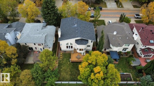 Aerial perspective of a detached residential property featuring a multi-level wood deck, gabled roofline, chimney stack, and a fenced backyard with mature trees - 225 Heagle Crescent Nw, Edmonton, AB 