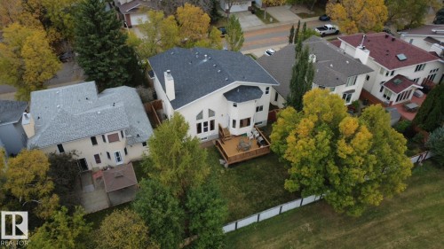 Aerial perspective of a detached residential property featuring a raised wood deck, multi-level architectural roofline, exterior chimney, and a fenced yard with mature trees - 225 Heagle Crescent Nw, Edmonton, AB 