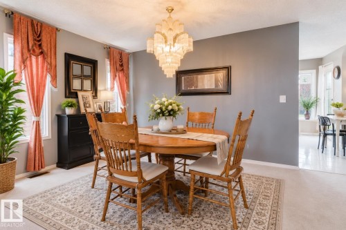 Multi-tiered crystal chandelier, neutral wall tones, and oversized windows providing natural light - 225 Heagle Crescent Nw, Edmonton, AB 