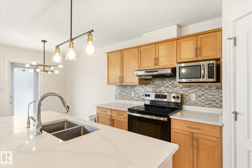 Kitchen featuring light wood cabinetry, a mosaic tile backsplash, stainless steel appliances, and a double basin sink - 2550 Rabbit Hill Road Nw, Edmonton, AB 