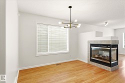 Hardwood flooring, tiled fireplace surround, contemporary chandelier, recessed lighting, and a large window with blinds - 