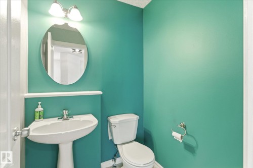 Pedestal sink with chrome faucet, oval mirror, and wall-mounted lighting fixture - 2550 Rabbit Hill Road Nw, Edmonton, AB 