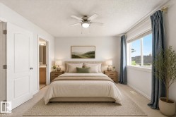Carpeted bedroom featuring a ceiling fan with integrated lighting, a large window with roller shades, and an arched panel door - 