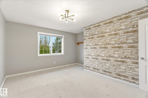Wall-mounted lighting fixture, window with exterior landscaping, feature wall with wood-look paneling, and wall-to-wall carpeting - 2550 Rabbit Hill Road Nw, Edmonton, AB 