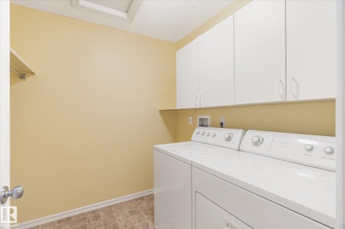 Laundry room featuring white cabinetry, a built-in shelf, and tile flooring - 2550 Rabbit Hill Road Nw, Edmonton, AB 