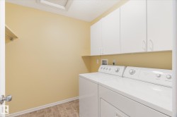 Laundry room featuring white cabinetry, a built-in shelf, and tile flooring - 