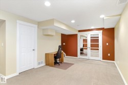 Recessed lighting, neutral carpeting, and a contrasting accent wall with white trim - 